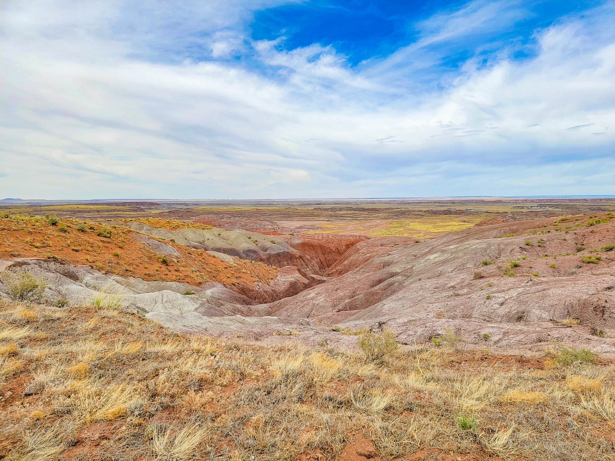 Badland formations with layered red and gray soil visible on the parcel in Apache County, Arizona.