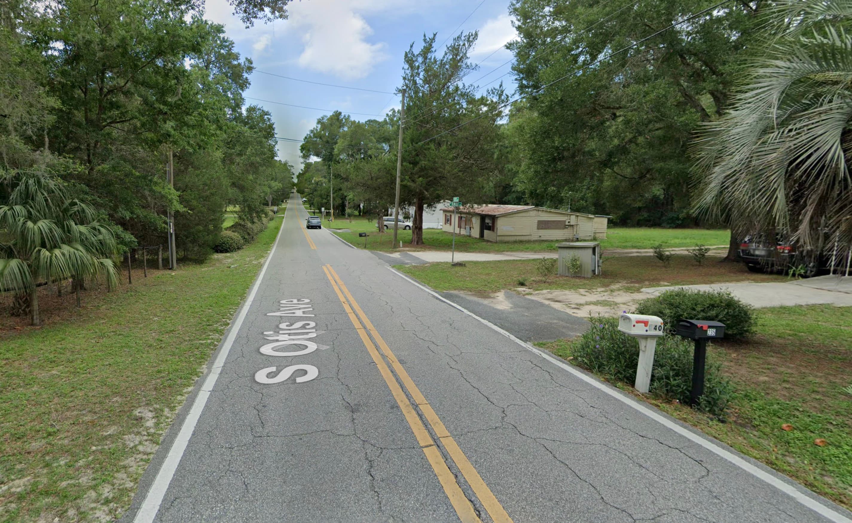 Paved road with mature trees on both sides and residential development in Citrus County, Florida.