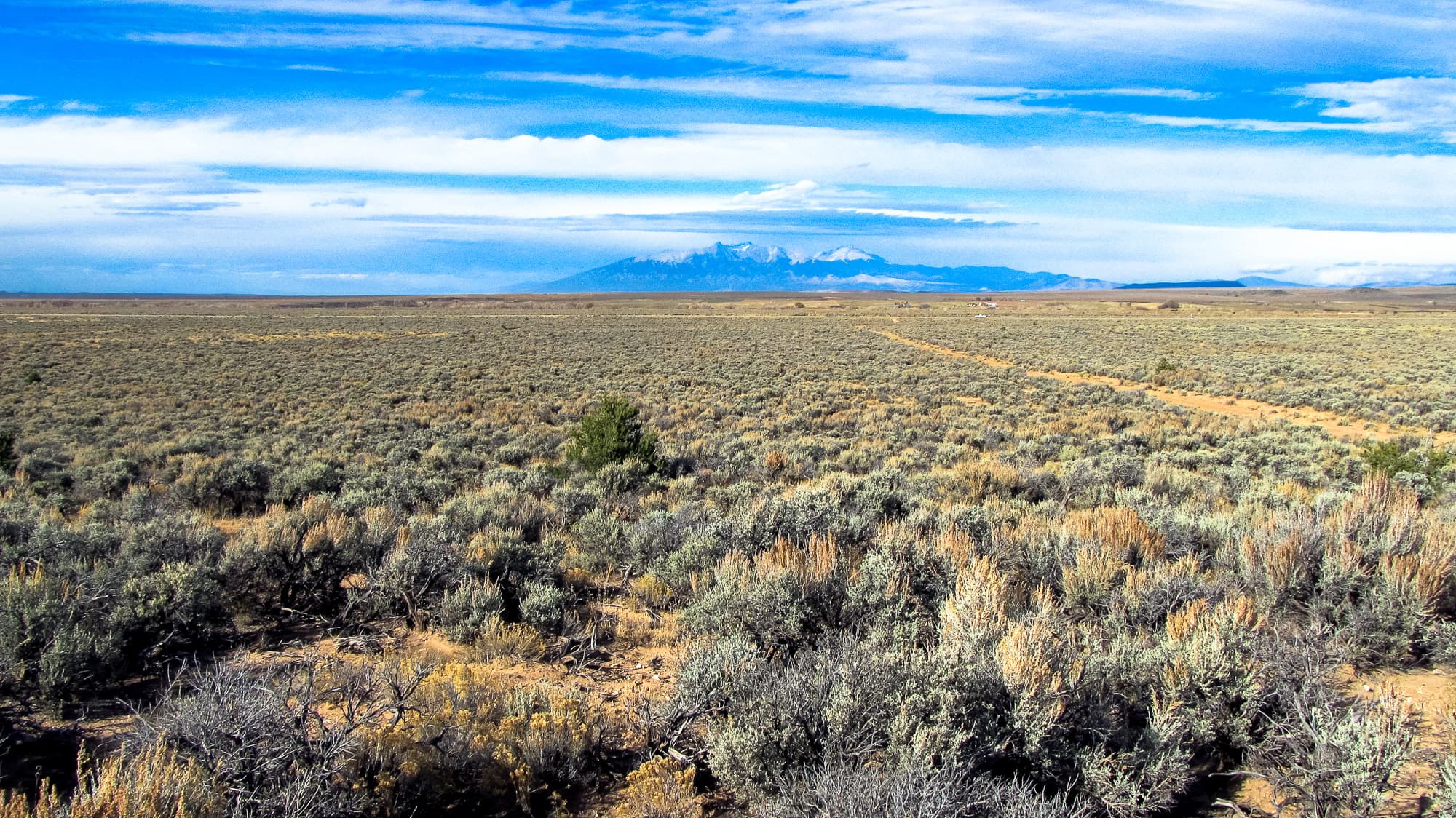Sagebrush plateau with snowy mountain range on the horizon in Costilla County, Colorado.