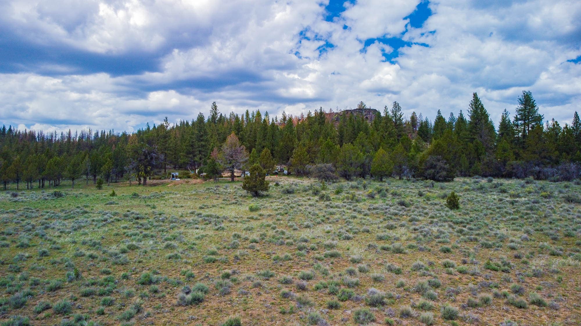 Drone photo capturing the parcel with conifer forest and mountains visible on the horizon in Klamath County, Oregon.