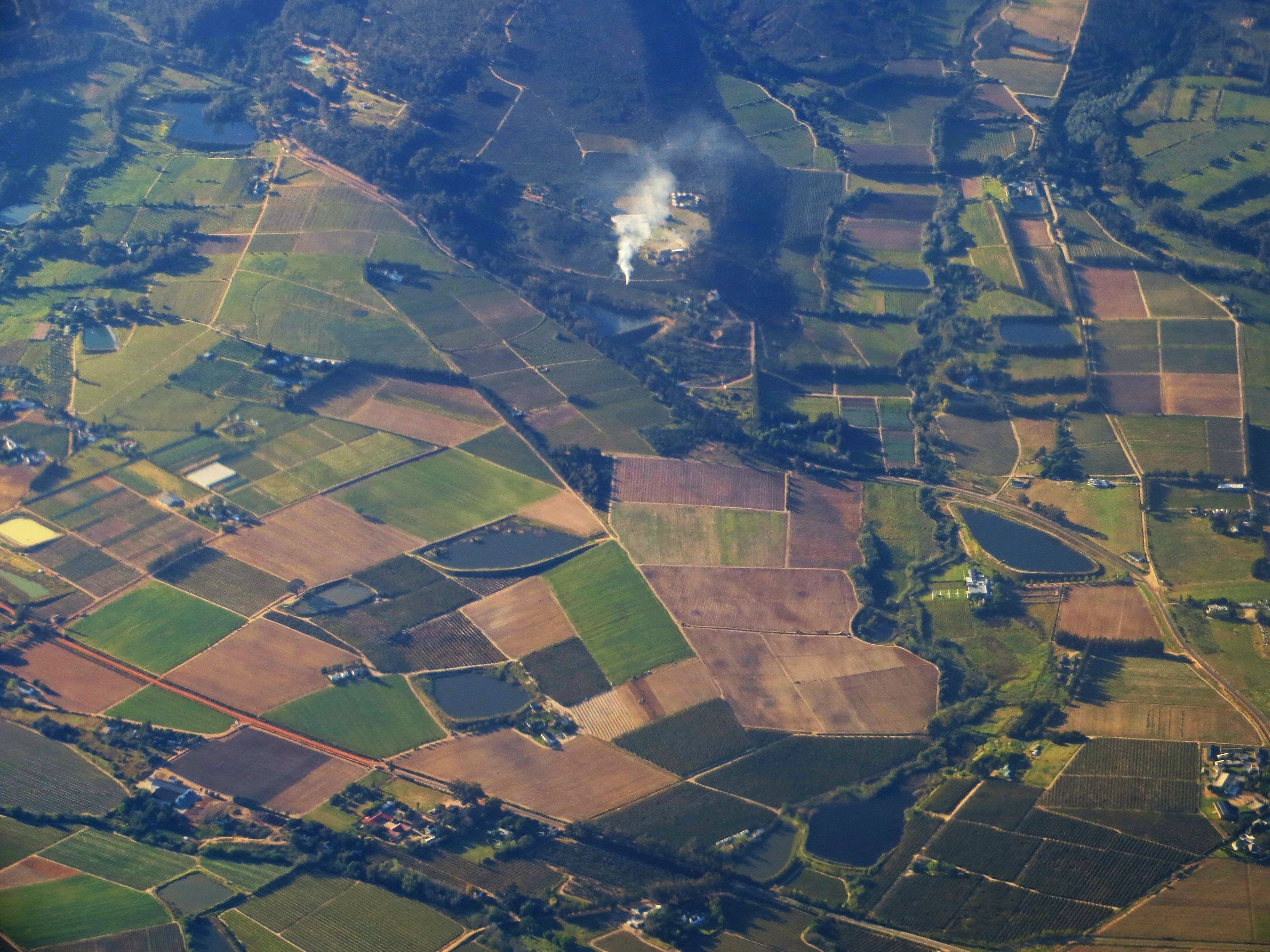 Aerial view of farmland divided into dozens of irregular parcels, with narrow roads and field tracks running between them.